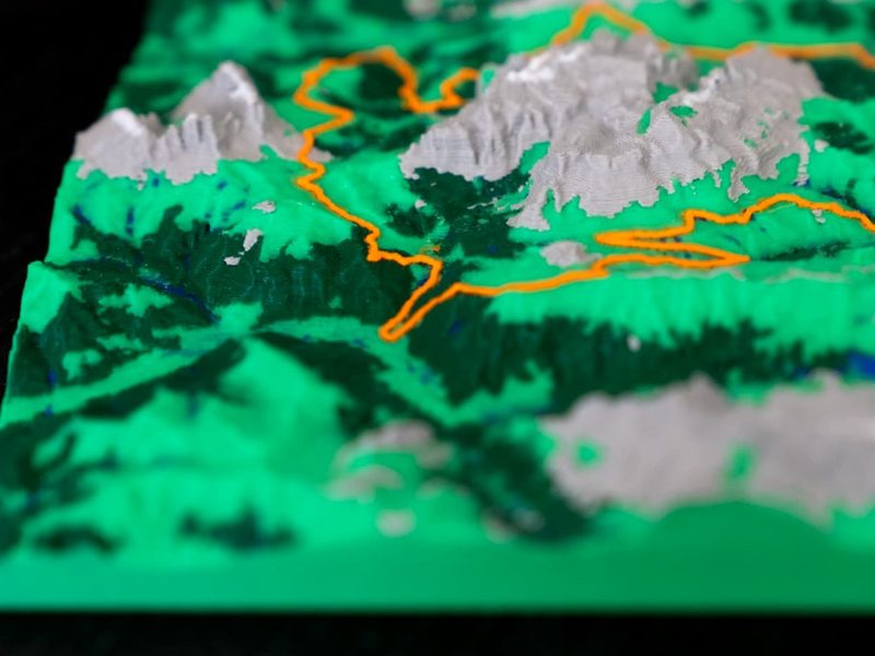 Angled close-up of a 3D printed elevation map showing terrain relief and orange route