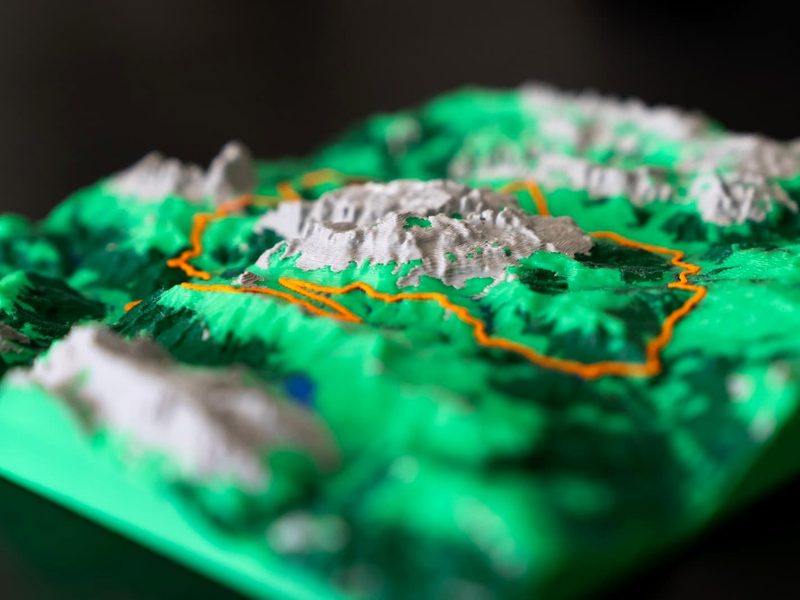 Close-up of a 3D printed elevation relief with an orange GPX route across green terrain